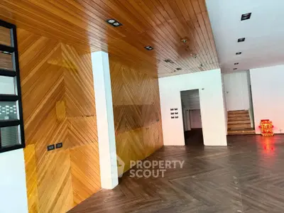 Modern interior with stylish wood paneling and sleek flooring, featuring a staircase and ambient lighting.