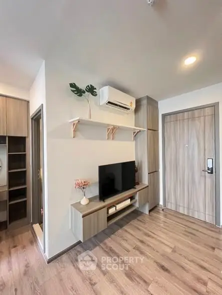 Modern living room with wooden flooring and wall-mounted TV in stylish apartment.