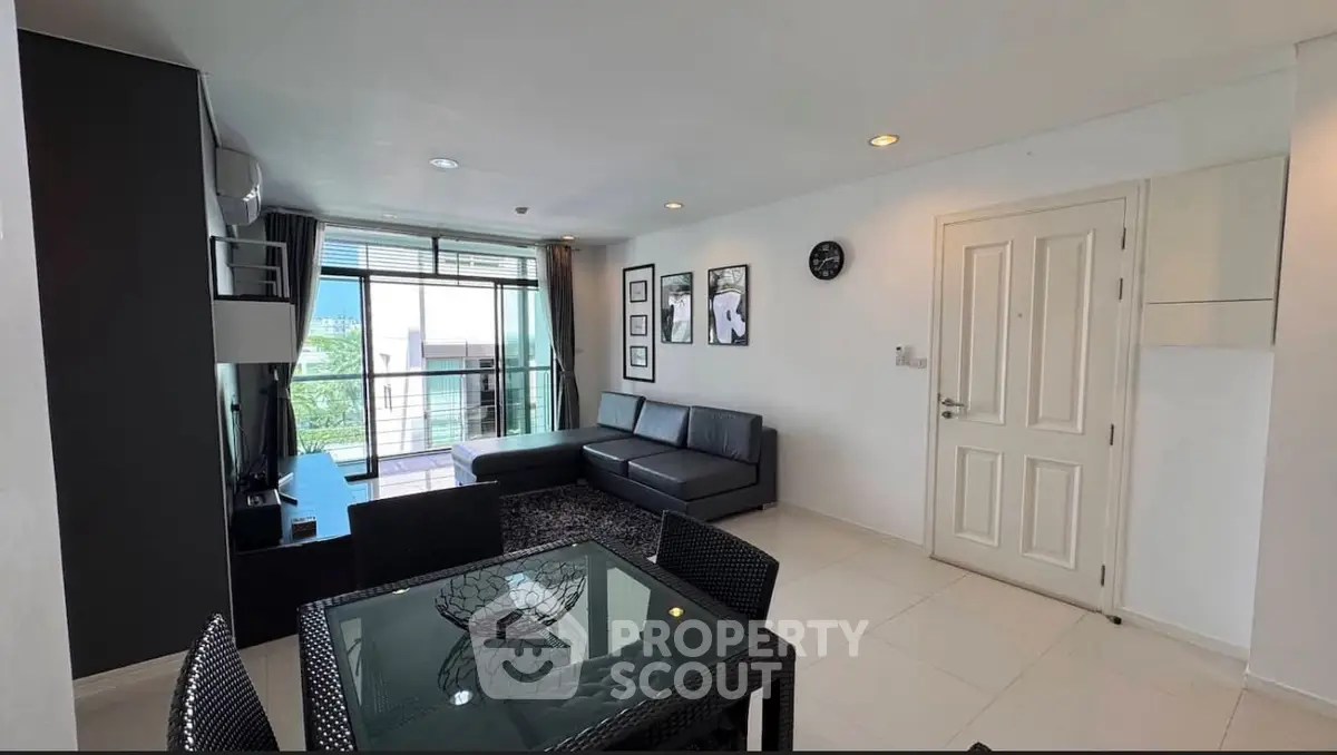 Modern living room with sleek black furniture and balcony view