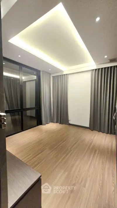 Spacious modern bedroom with wooden flooring and large windows in luxury apartment.