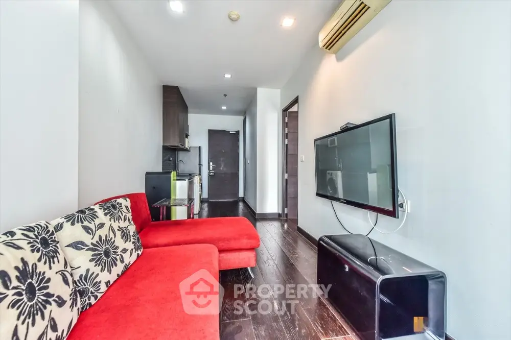 Modern living room with red sofa and wall-mounted TV in sleek apartment.