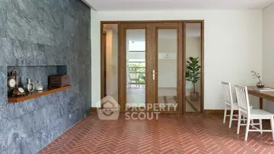 Elegant entrance with brick flooring and wooden doors leading to a bright interior, perfect for modern living.