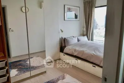 Modern bedroom with city view, mirrored closet, and stylish decor in urban apartment.