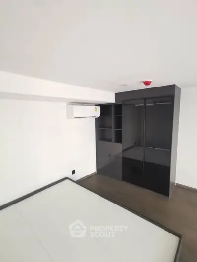 Modern bedroom with sleek black wardrobe and air conditioning unit