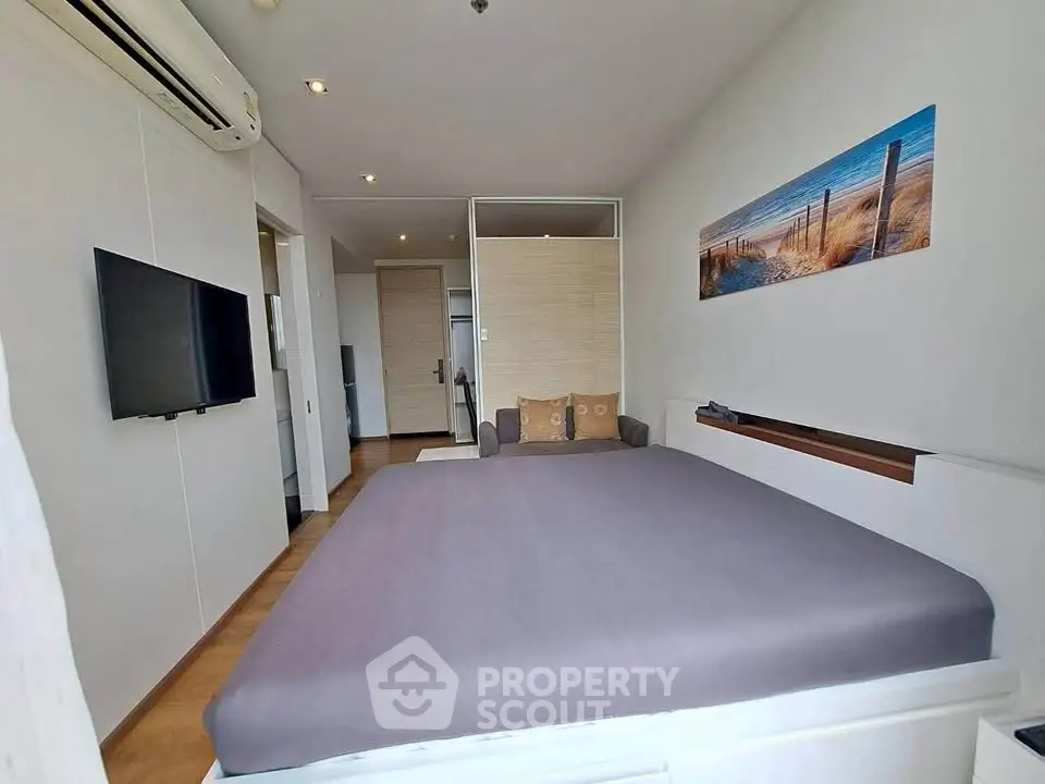 Modern bedroom with stylish decor and wall art, featuring a comfortable bed and mounted TV.