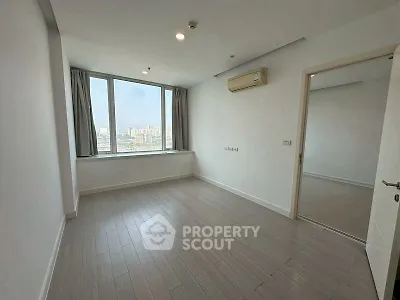 Spacious empty bedroom with large window and city view