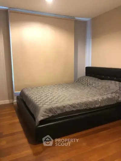 Cozy bedroom with modern decor and wooden flooring, featuring a comfortable bed and soft lighting.