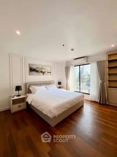 Spacious bedroom with city view and elegant decor, featuring hardwood floors and modern furnishings.