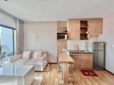 Modern living room with open kitchen, featuring sleek wooden floors and contemporary furniture.