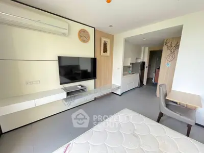 Modern studio apartment with sleek design, featuring a wall-mounted TV, air conditioning, and compact kitchen area.