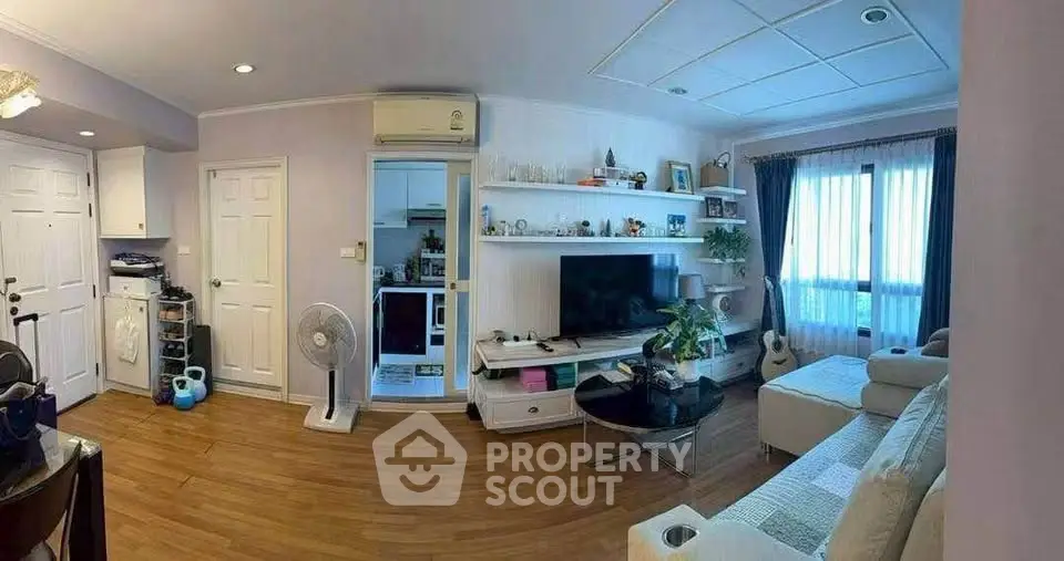 Spacious living room with modern decor and natural light, featuring a cozy sofa and entertainment center.