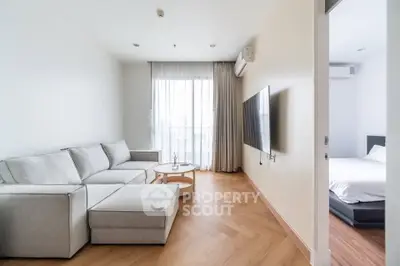 Modern living room with sleek furniture and natural light, adjacent to a cozy bedroom.