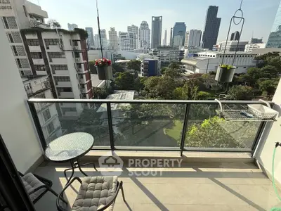 Stunning balcony view of city skyline with modern glass railing and cozy seating area.