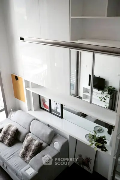 Modern living room with sleek white cabinetry and cozy gray sofa