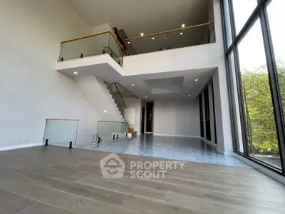 Spacious modern living room with high ceilings and large windows offering natural light and scenic views.