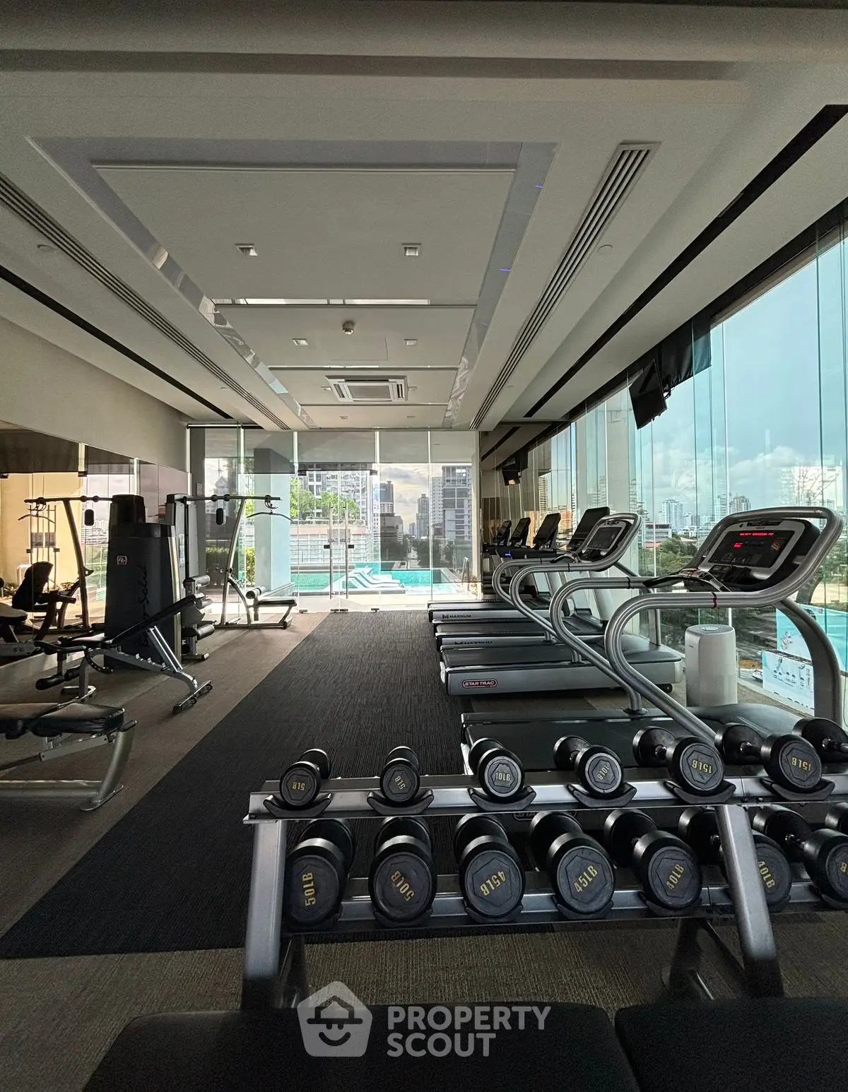 Modern gym with city view and state-of-the-art equipment in luxury building.
