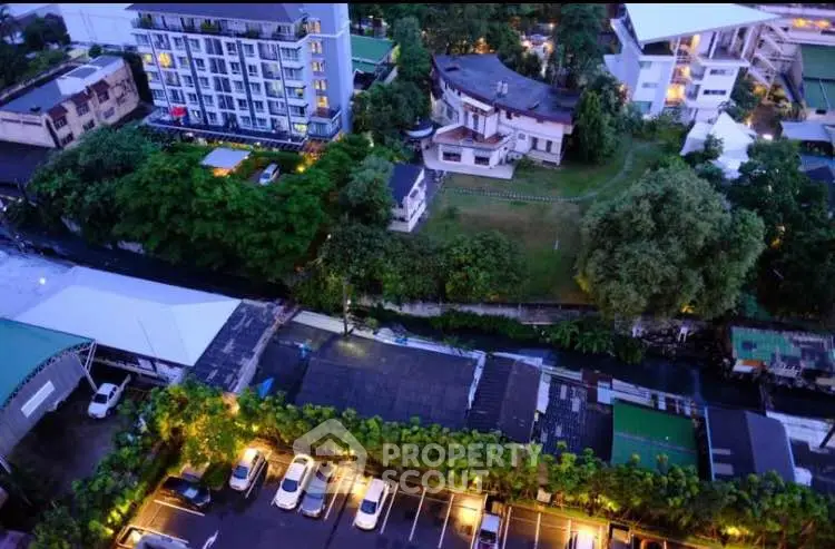 Aerial view of residential buildings and lush greenery in an urban setting at dusk.