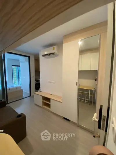 Modern apartment interior with sleek design and air conditioning, featuring a cozy living area and mirrored storage.