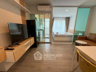 Modern studio apartment with open layout, featuring a cozy living area and bedroom separated by glass doors.