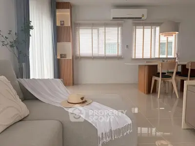 Modern living room with cozy sofa and dining area, featuring elegant decor and natural light.