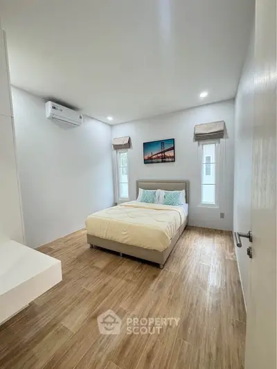 Bright and cozy bedroom with modern decor and wooden flooring, perfect for relaxation.