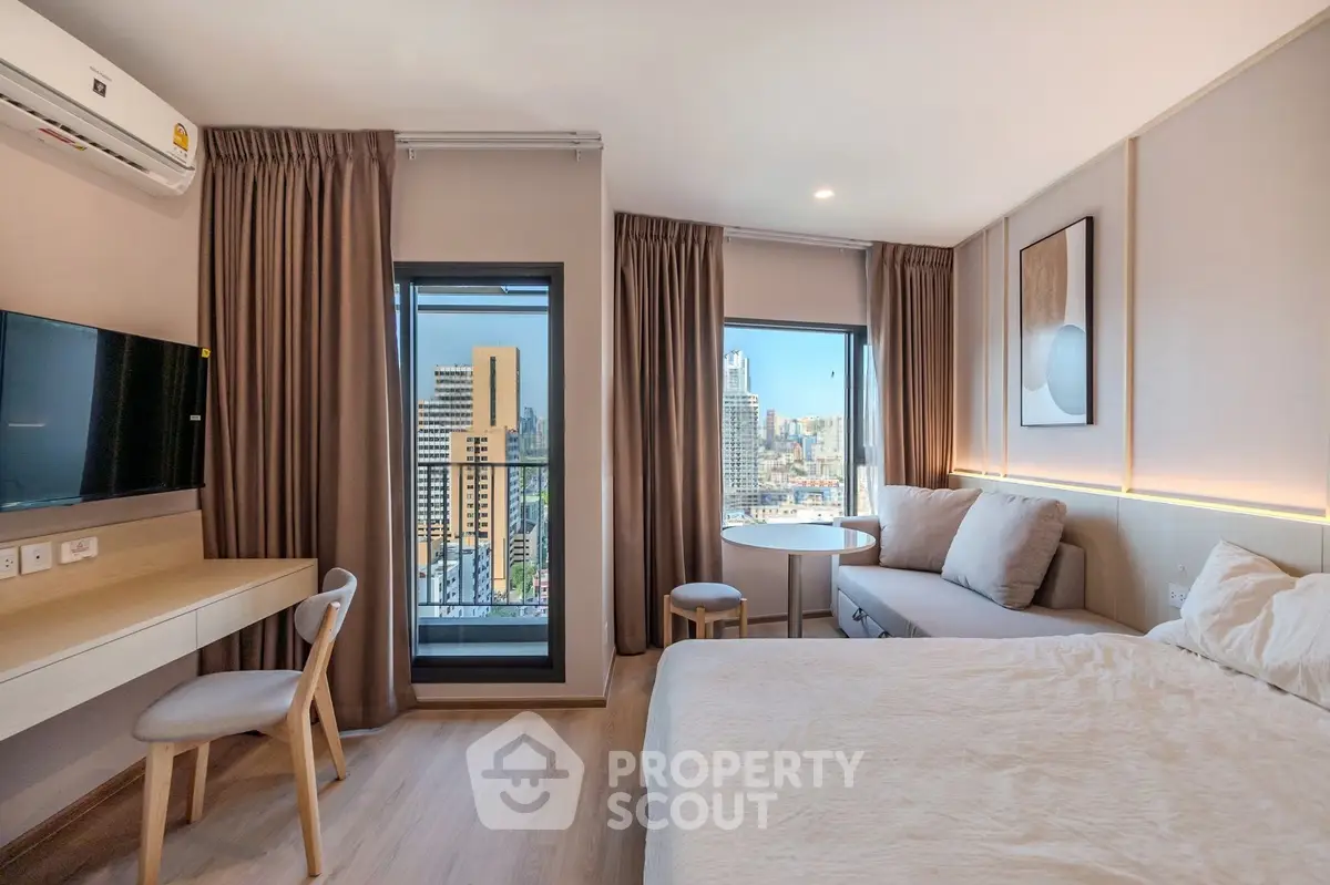Modern bedroom with city view, featuring cozy seating area and stylish decor.