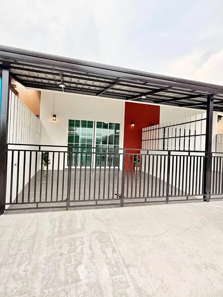 Modern house exterior with gated entrance and covered parking area.