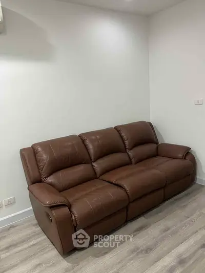 Spacious living room with a luxurious brown leather sofa and modern flooring.