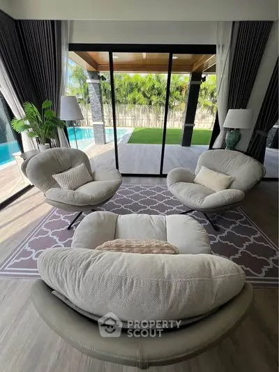 Luxurious living room with modern furniture and poolside view, perfect for relaxation and entertaining.
