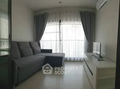 Modern living room with gray sofa, large window, and sleek TV setup.