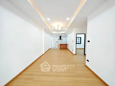Spacious open-plan living room with modern kitchen and elegant lighting in a contemporary apartment.