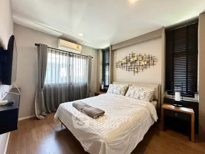 Cozy bedroom with modern decor and natural light, featuring a stylish wall art and wooden flooring.