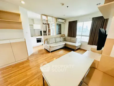 Spacious modern living room with wooden flooring and large windows offering city views.