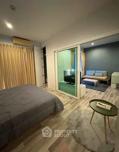 Modern apartment interior with cozy bedroom and stylish living area, featuring sleek furniture and warm lighting.