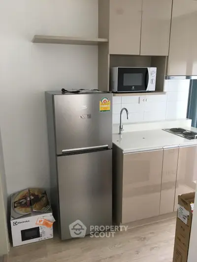 Modern kitchen with stainless steel fridge and microwave, sleek cabinetry, and compact design.