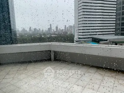 Stunning city view from a high-rise balcony on a rainy day, perfect for urban living.