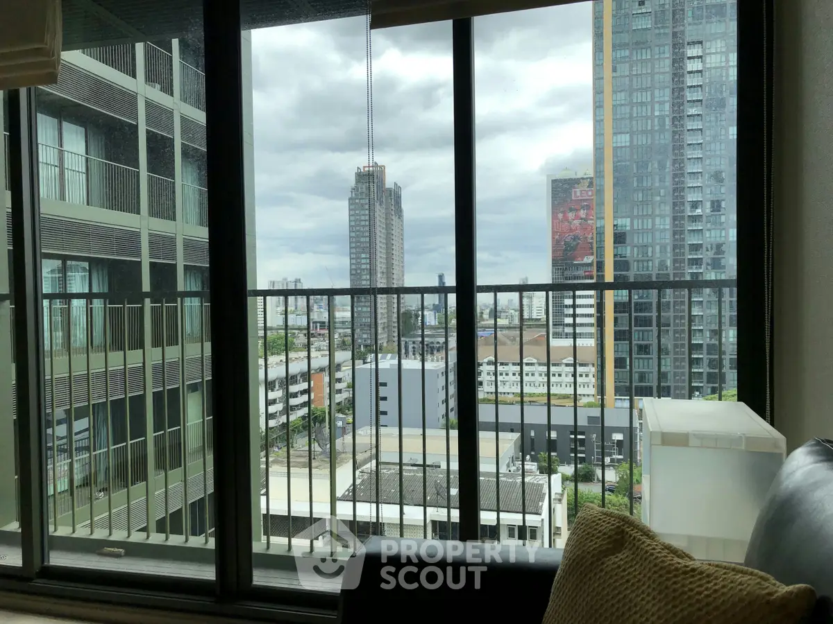 Stunning cityscape view from modern apartment balcony with large glass windows.