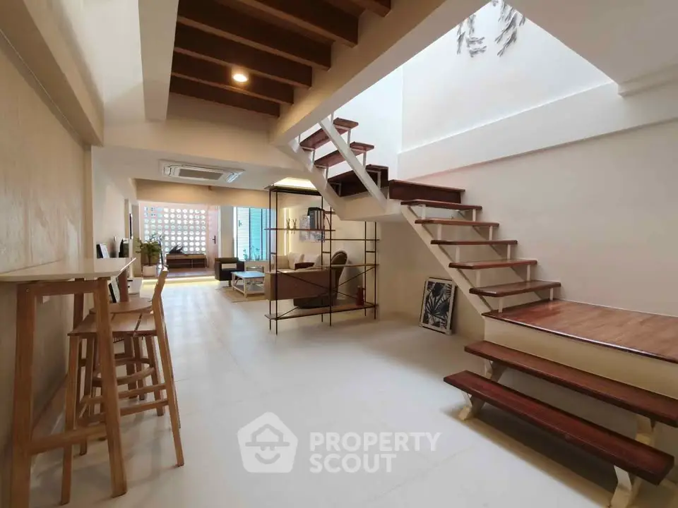 Modern open-plan living area with stylish staircase and natural light