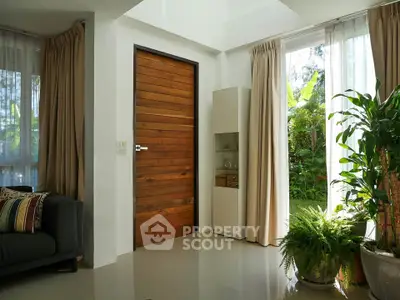 Charming living room with garden view, featuring wooden door and lush indoor plants.