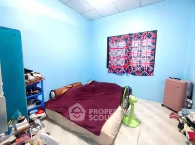 Cozy bedroom with minimalist decor and vibrant blue walls, featuring a comfortable bed and practical storage solutions.