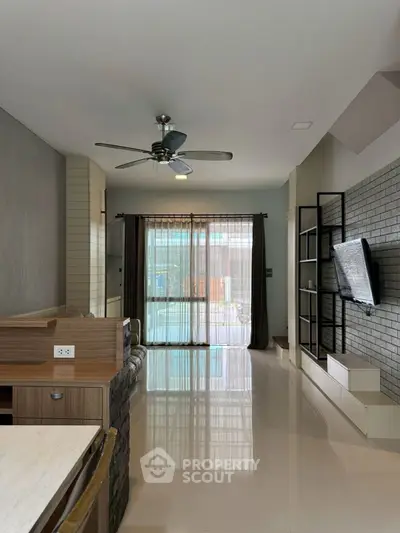 Modern living room with sleek design, ceiling fan, and large window for natural light.