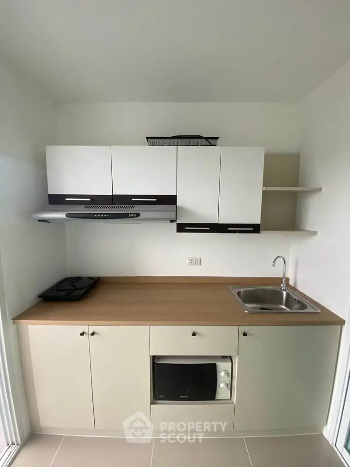 Modern compact kitchen with sleek cabinetry and built-in appliances, ideal for efficient cooking in small spaces.