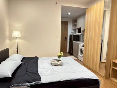 Cozy bedroom with modern kitchenette and washing machine in stylish apartment.
