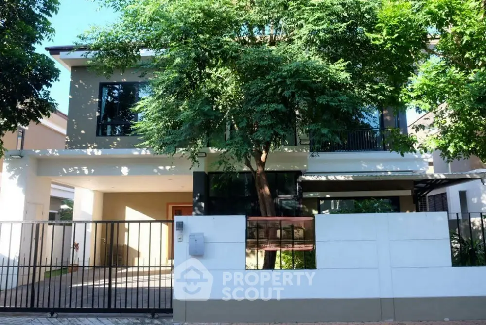 Modern two-story house with lush greenery and gated entrance, perfect for family living.