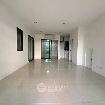 Spacious modern living room with sleek tile flooring and large windows for natural light.