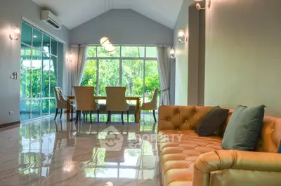 Spacious living room with elegant dining area and large windows offering lush garden views.