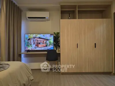 Modern bedroom with built-in wardrobe and wall-mounted TV, featuring sleek design and cozy ambiance.