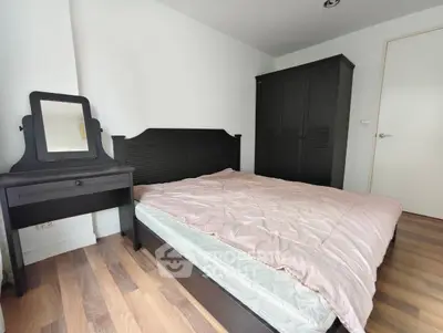 Cozy bedroom with wooden flooring and elegant dark furniture, perfect for relaxation.