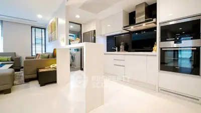 Modern open-layout kitchen with sleek appliances and adjacent cozy living room.