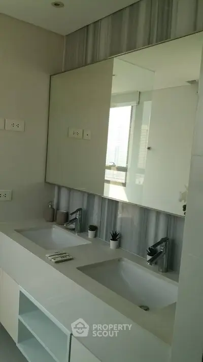 Modern bathroom with dual sinks and large mirror in luxury apartment.